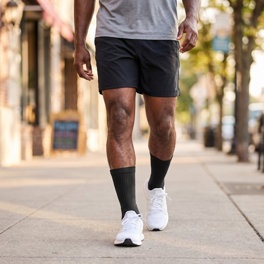 Man walking down a city street wearing black V-Socks compression socks with white sneakers